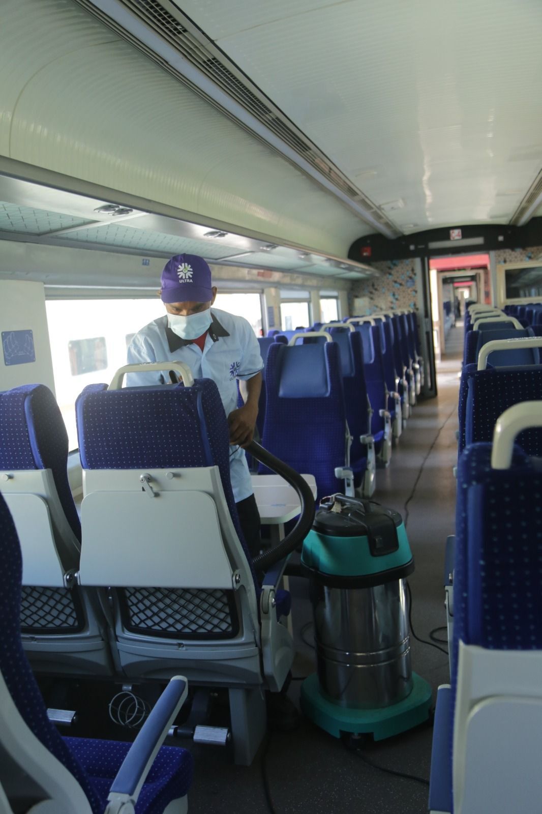 Ultra staff vacuuming seats inside a Vande Bharat Express coach