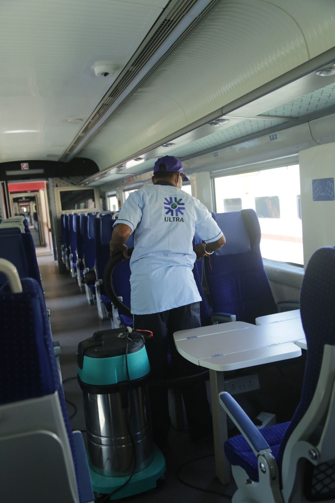 Ultra staff vacuuming seats inside a Vande Bharat Express coach
